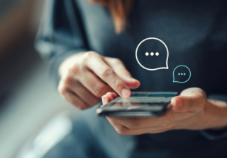 a woman's hands holding a mobile phone, showing chat bubbles